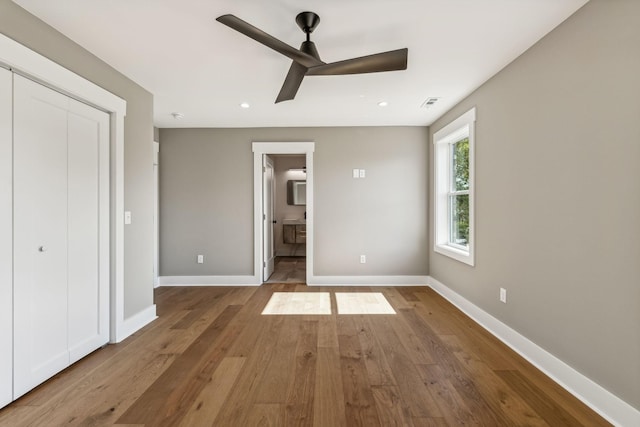 unfurnished bedroom with ceiling fan, wood-type flooring, and ensuite bathroom