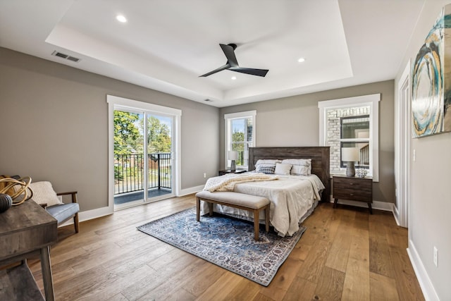 bedroom with a raised ceiling, access to exterior, and light hardwood / wood-style floors