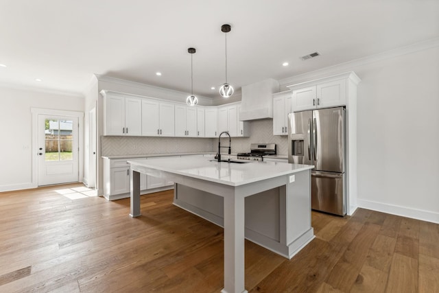 kitchen featuring stainless steel appliances, white cabinetry, custom range hood, and a center island with sink