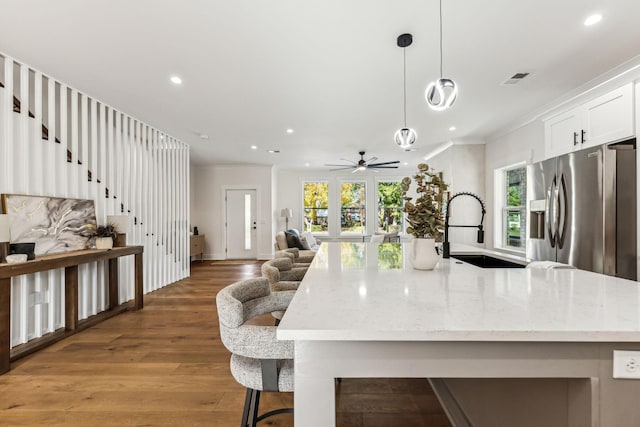 kitchen with white cabinetry, sink, hanging light fixtures, stainless steel refrigerator with ice dispenser, and a healthy amount of sunlight