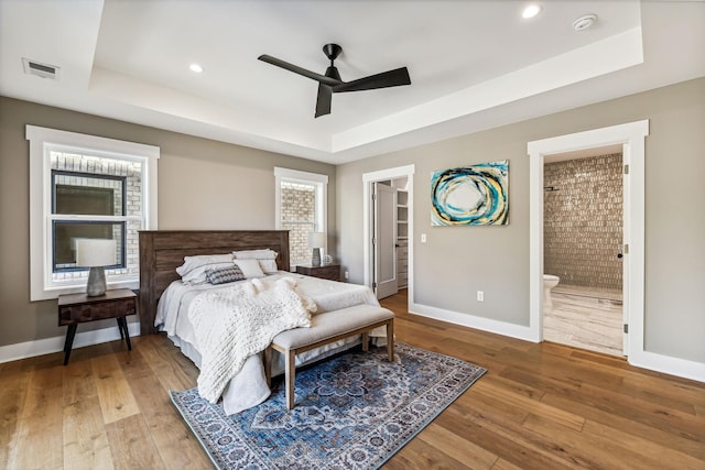 bedroom featuring a raised ceiling, connected bathroom, a spacious closet, and hardwood / wood-style floors