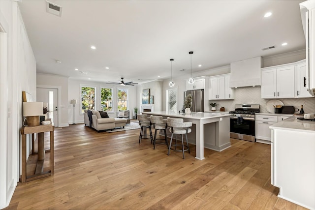 kitchen featuring white cabinetry, a center island, custom range hood, pendant lighting, and stainless steel appliances