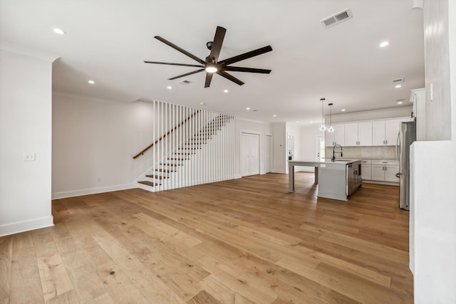 unfurnished living room with ceiling fan, sink, and light hardwood / wood-style flooring