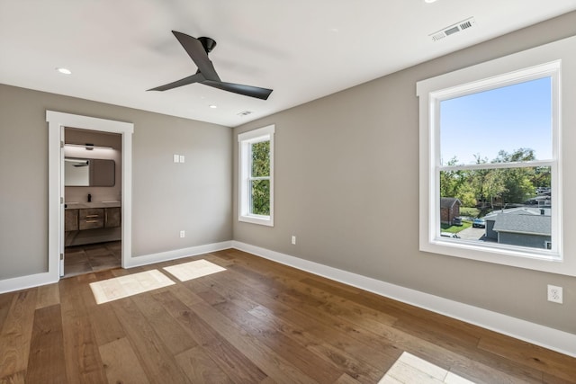 unfurnished bedroom with ceiling fan, wood-type flooring, and connected bathroom