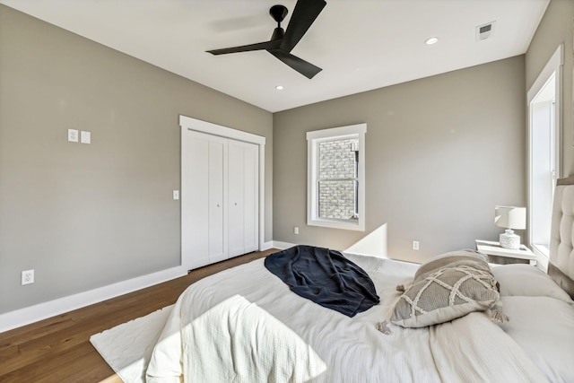 bedroom with dark hardwood / wood-style floors, ceiling fan, and a closet