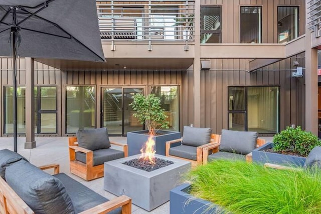 view of patio / terrace featuring a balcony and an outdoor living space with a fire pit