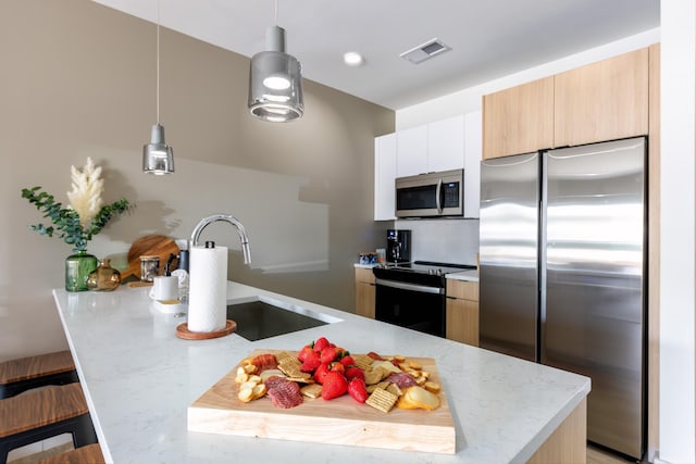 kitchen featuring white cabinetry, sink, hanging light fixtures, stainless steel appliances, and light stone countertops