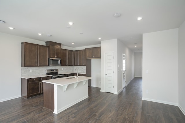 kitchen featuring stainless steel appliances, tasteful backsplash, sink, and a center island with sink