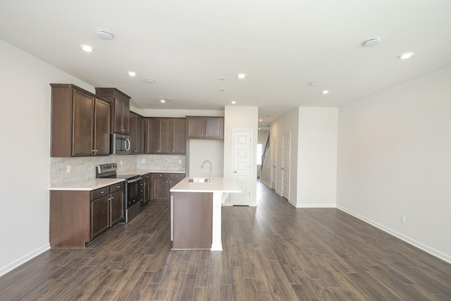 kitchen featuring appliances with stainless steel finishes, dark hardwood / wood-style floors, an island with sink, sink, and backsplash