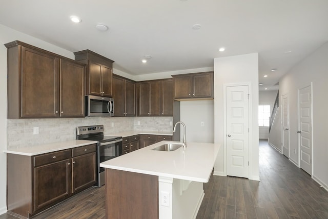 kitchen with sink, stainless steel appliances, tasteful backsplash, a center island with sink, and dark hardwood / wood-style flooring