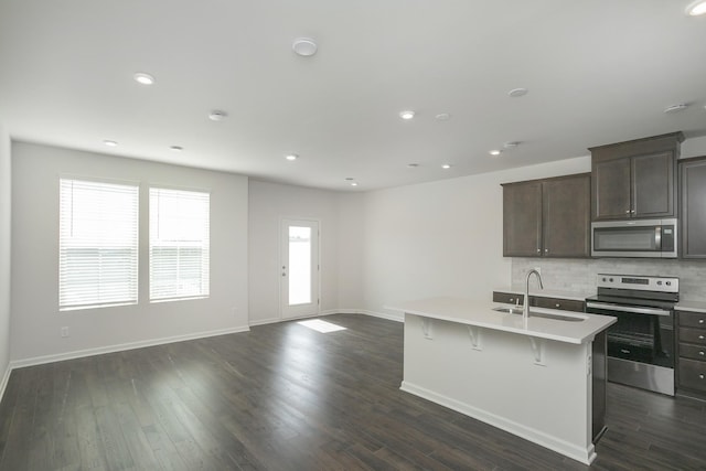 kitchen featuring an island with sink, stainless steel appliances, dark hardwood / wood-style floors, and sink