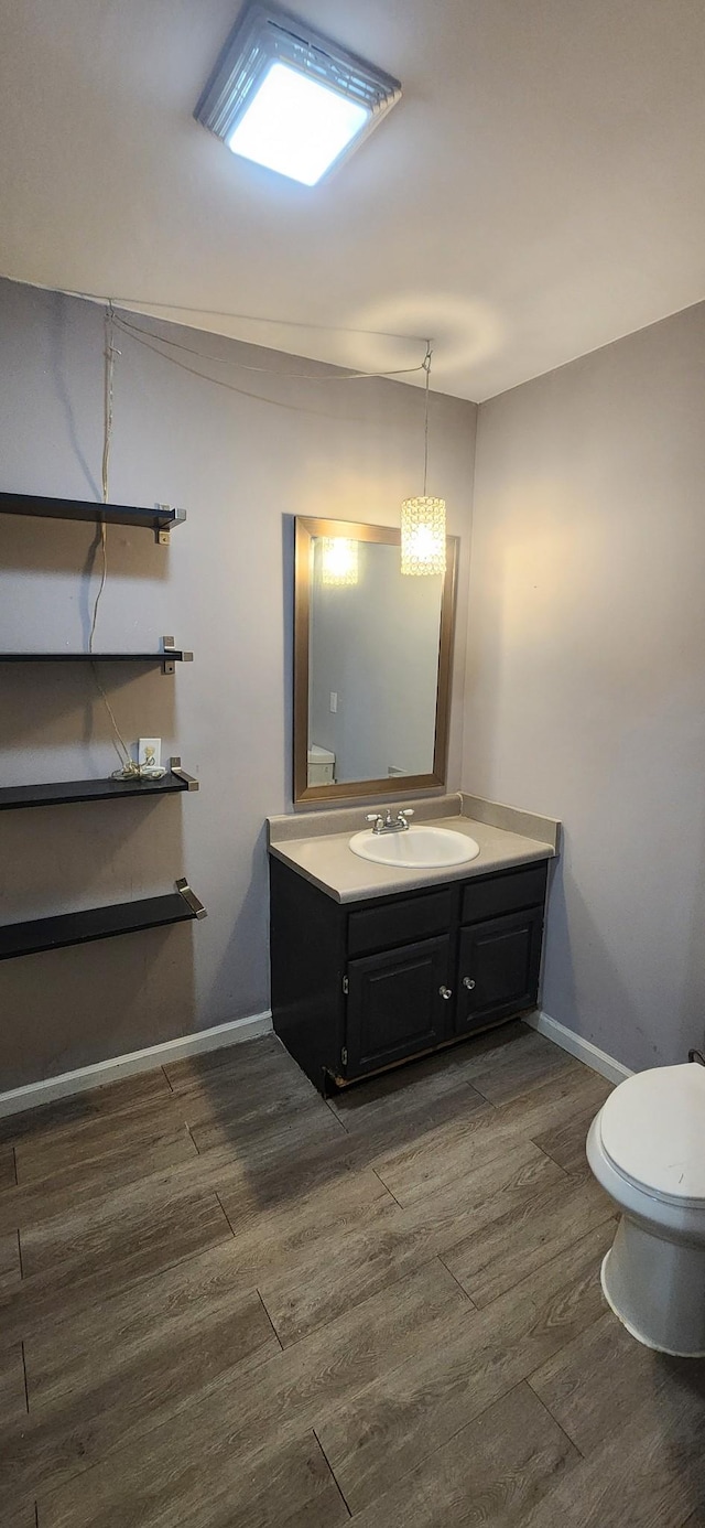 bathroom with hardwood / wood-style flooring, vanity, and toilet