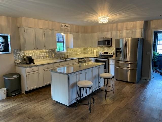 kitchen featuring a kitchen island, appliances with stainless steel finishes, sink, white cabinets, and a kitchen breakfast bar