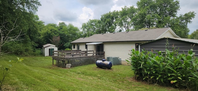 rear view of property featuring a yard, cooling unit, a deck, and a storage shed