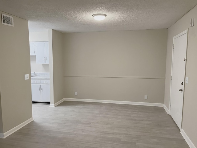 unfurnished room with a textured ceiling and light hardwood / wood-style flooring