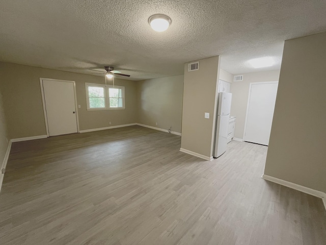 spare room with ceiling fan, light hardwood / wood-style flooring, and a textured ceiling