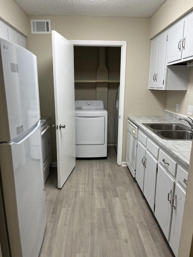 kitchen featuring white cabinetry, washer / dryer, sink, and refrigerator