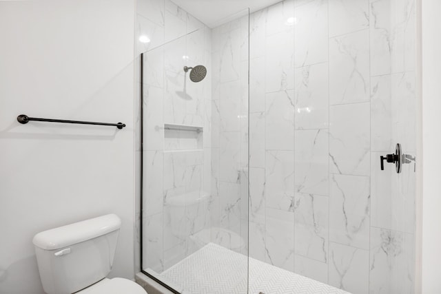 bathroom with a tile shower and toilet