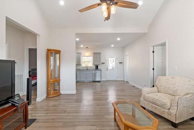 living room featuring ceiling fan, wood-type flooring, and sink