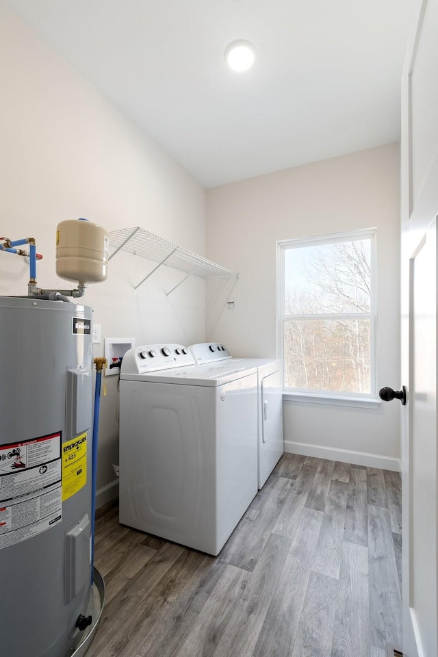 clothes washing area featuring washer and dryer, electric water heater, and light wood-type flooring