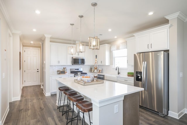 kitchen with appliances with stainless steel finishes, decorative light fixtures, a center island, and white cabinets