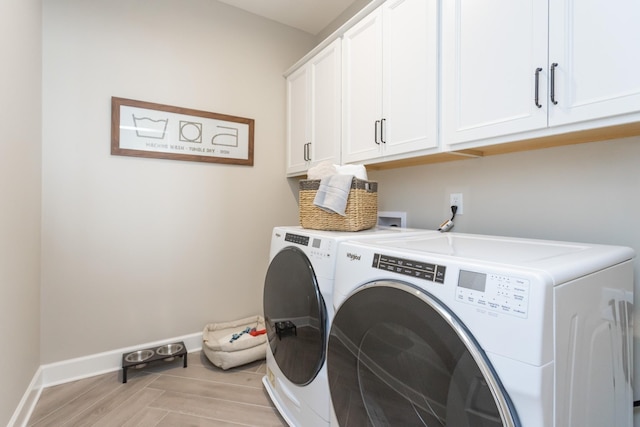 clothes washing area featuring washer and dryer and cabinets