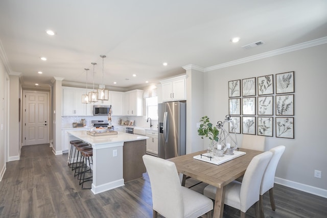 dining room with crown molding, sink, and dark hardwood / wood-style flooring