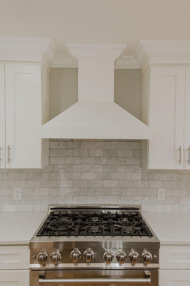 kitchen featuring white cabinets, premium range hood, tasteful backsplash, and stainless steel gas range