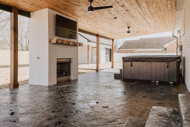 view of patio / terrace featuring an outdoor brick fireplace, a hot tub, and ceiling fan