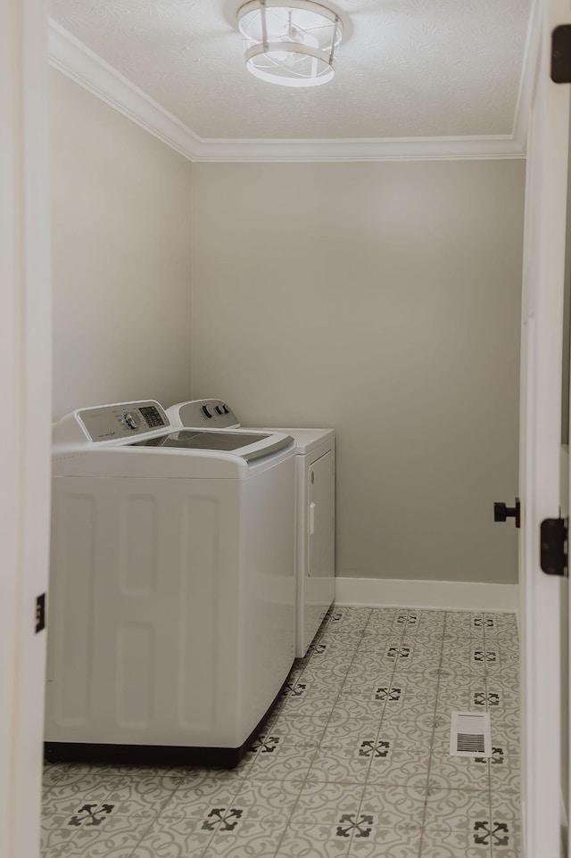 clothes washing area with crown molding and washing machine and clothes dryer