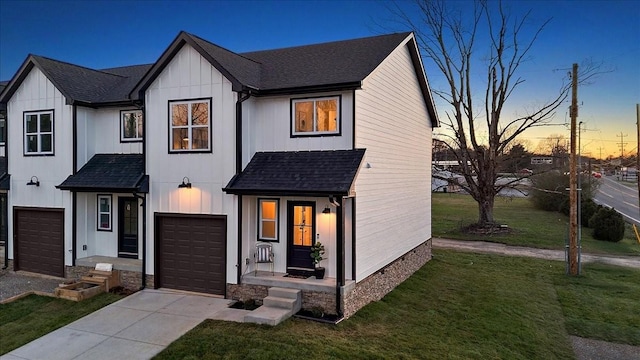 modern inspired farmhouse featuring a garage and a lawn