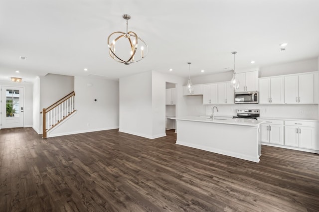 kitchen featuring sink, hanging light fixtures, stainless steel appliances, an island with sink, and white cabinets