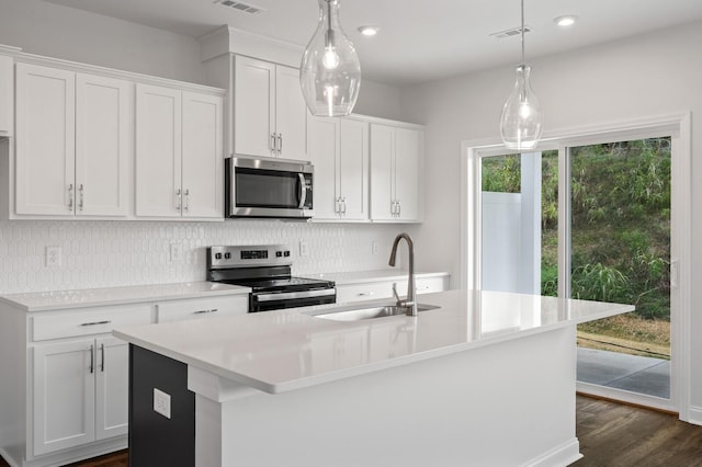 kitchen featuring white cabinetry, sink, stainless steel appliances, and a center island with sink