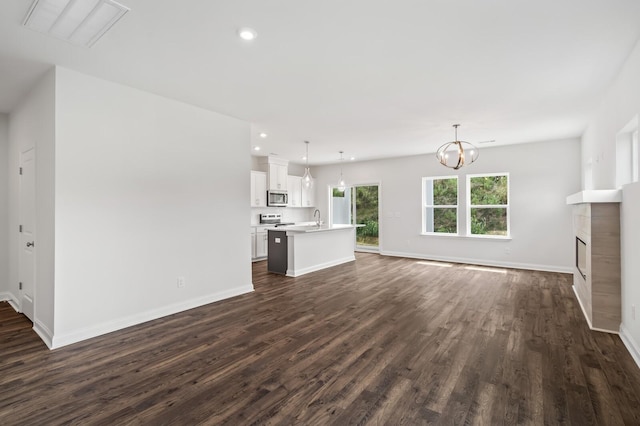 unfurnished living room featuring dark hardwood / wood-style flooring, a chandelier, and sink