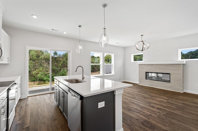 kitchen featuring an island with sink, stainless steel appliances, decorative light fixtures, and sink