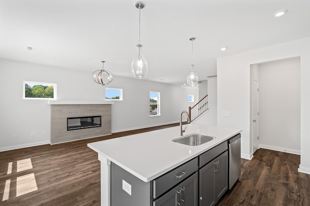 kitchen featuring pendant lighting, dishwasher, sink, gray cabinetry, and a kitchen island with sink