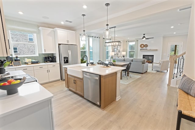 kitchen featuring appliances with stainless steel finishes, sink, an island with sink, and white cabinets