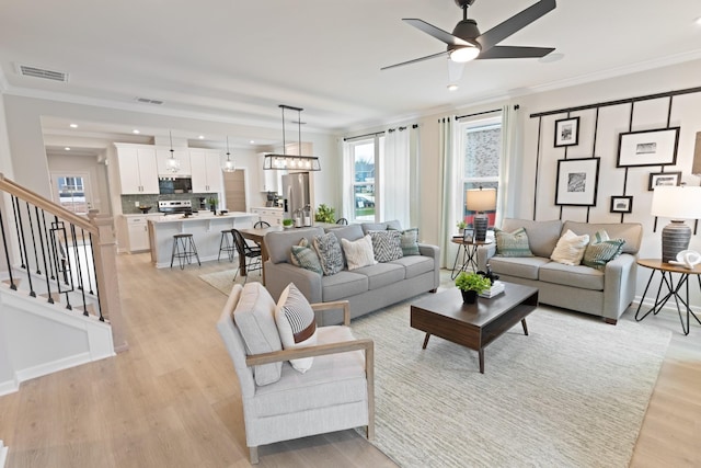 living room featuring crown molding, ceiling fan, and light hardwood / wood-style floors