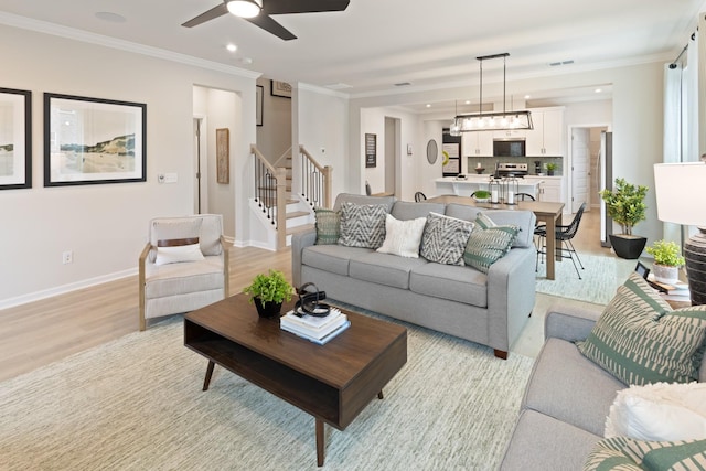 living room featuring ornamental molding, ceiling fan, and light hardwood / wood-style flooring