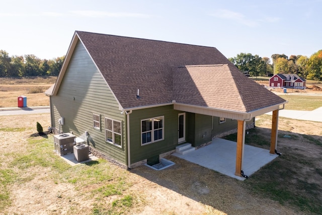 back of house featuring a lawn, central AC unit, and a patio area