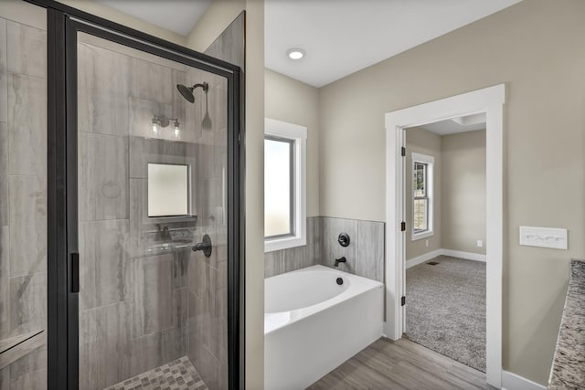 bathroom featuring plus walk in shower and hardwood / wood-style floors