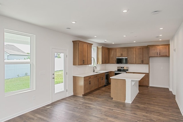 kitchen with sink, stainless steel appliances, tasteful backsplash, a kitchen island, and dark hardwood / wood-style flooring