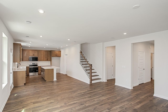 kitchen featuring dark wood-type flooring, sink, tasteful backsplash, a center island, and electric range