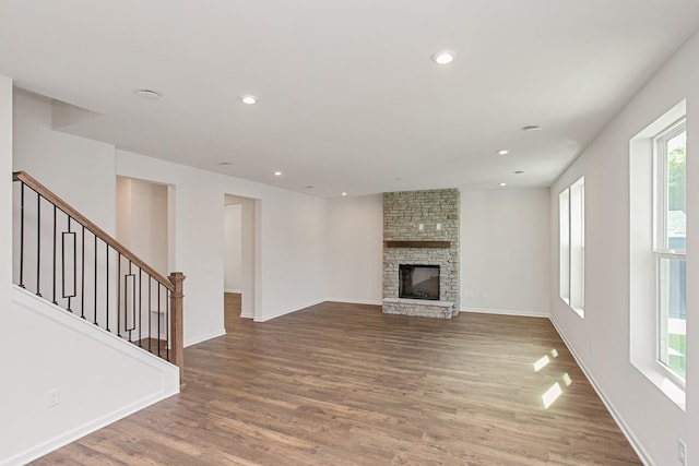 unfurnished living room featuring hardwood / wood-style flooring and a stone fireplace