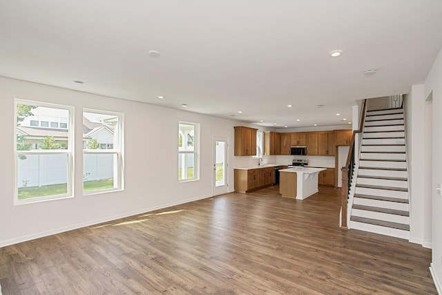 unfurnished living room featuring sink, a wealth of natural light, and dark hardwood / wood-style floors