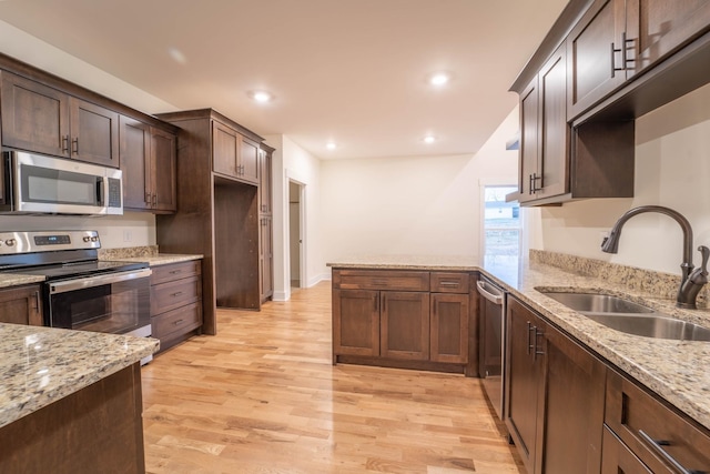 kitchen featuring sink, light hardwood / wood-style flooring, light stone countertops, and appliances with stainless steel finishes