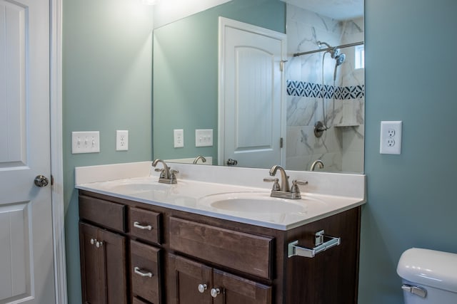 bathroom with a tile shower, vanity, and toilet