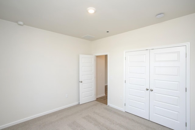 unfurnished bedroom featuring a closet and light carpet