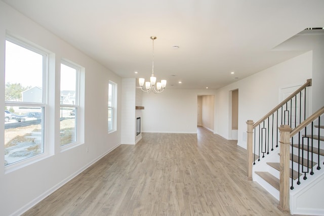 interior space with an inviting chandelier, a large fireplace, and light wood-type flooring