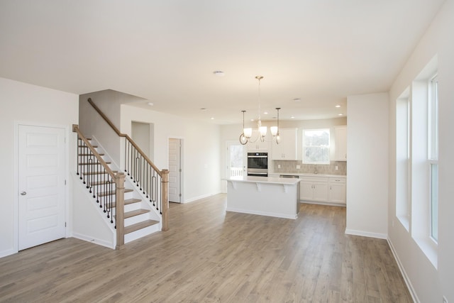 kitchen featuring white cabinetry, decorative light fixtures, light hardwood / wood-style flooring, and a center island